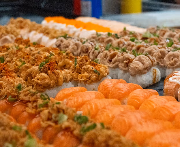 Rows of assorted sushi rolls with various toppings.